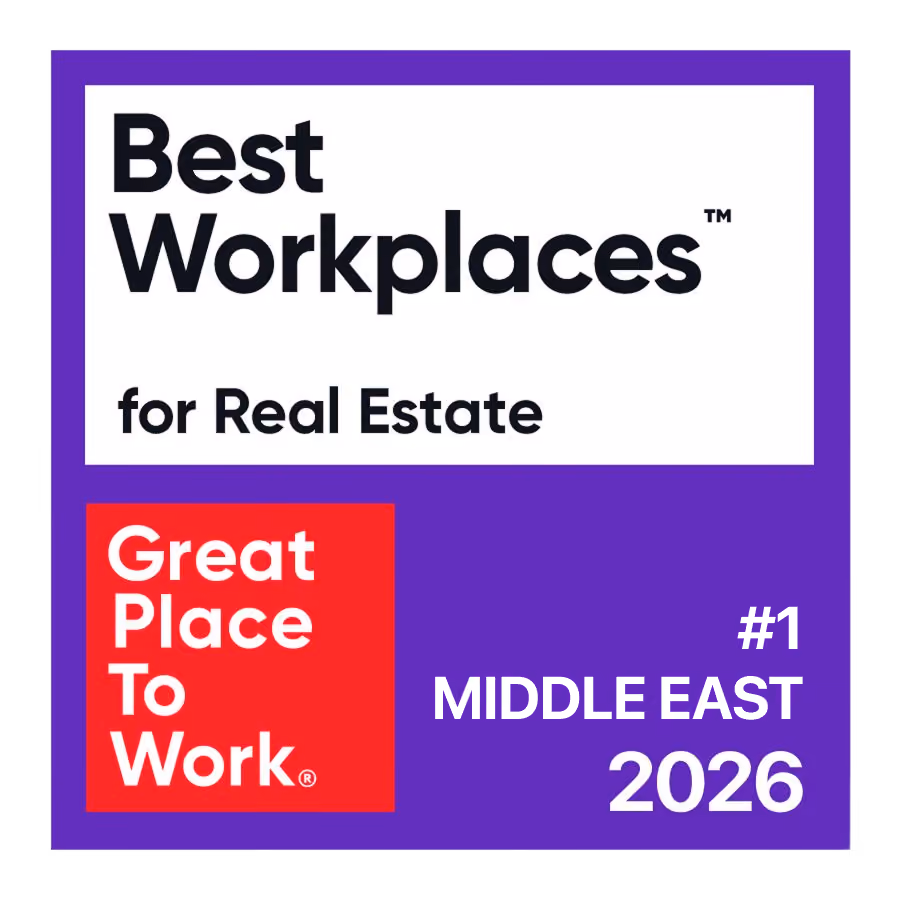 Badge stating 'Best Workplaces for Real Estate' with a red square containing 'Great Place To Work' logo and text '#1 Middle East 2026' on a purple background.